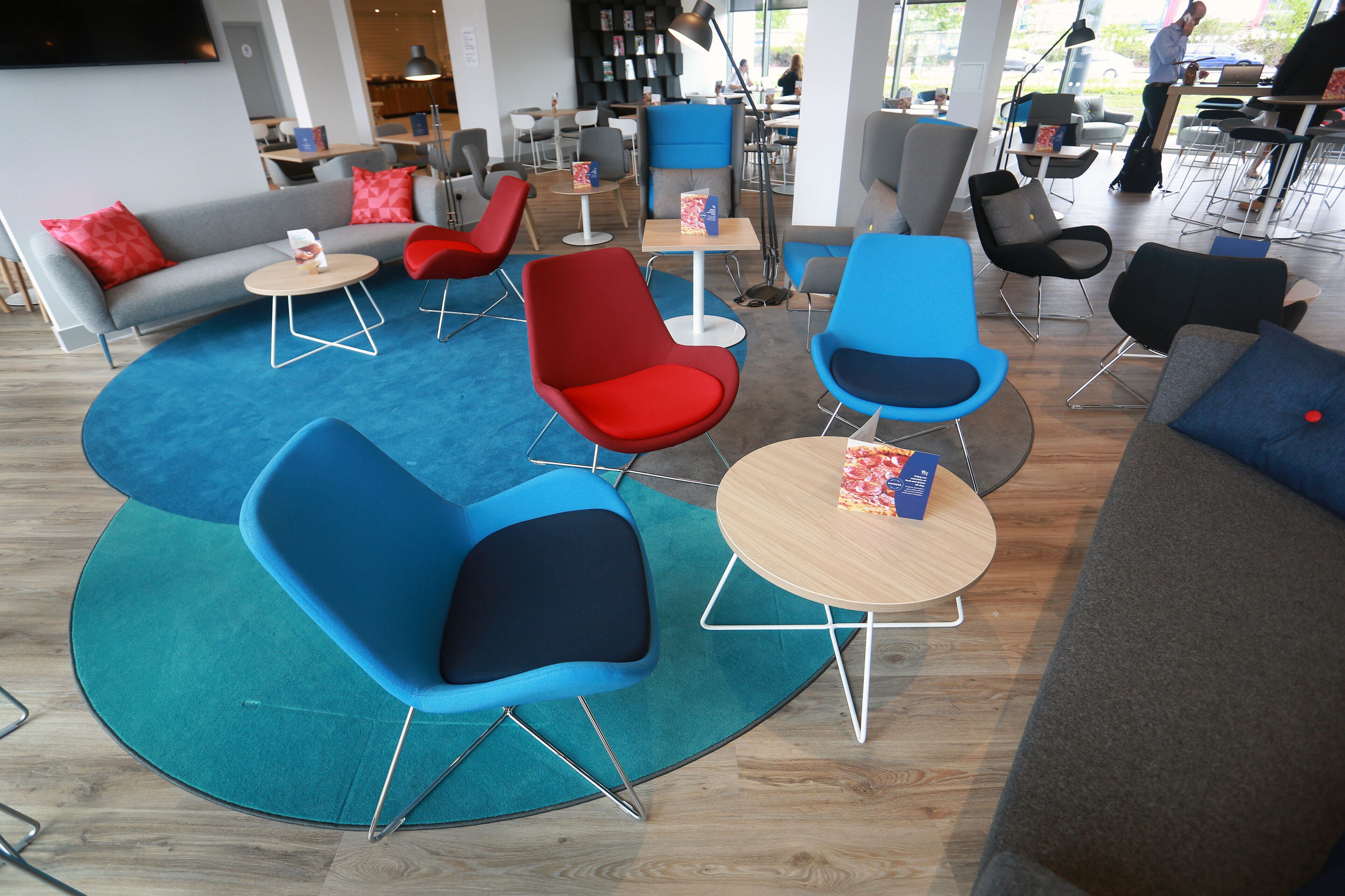 A modern lounge area with multiple seating options including sofas and chairs, arranged around a central coffee table.