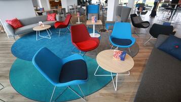 A modern lounge area with multiple seating options including sofas and chairs, arranged around a central coffee table.
