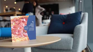 A table with a menu card and a grey armchair with a blue pillow.