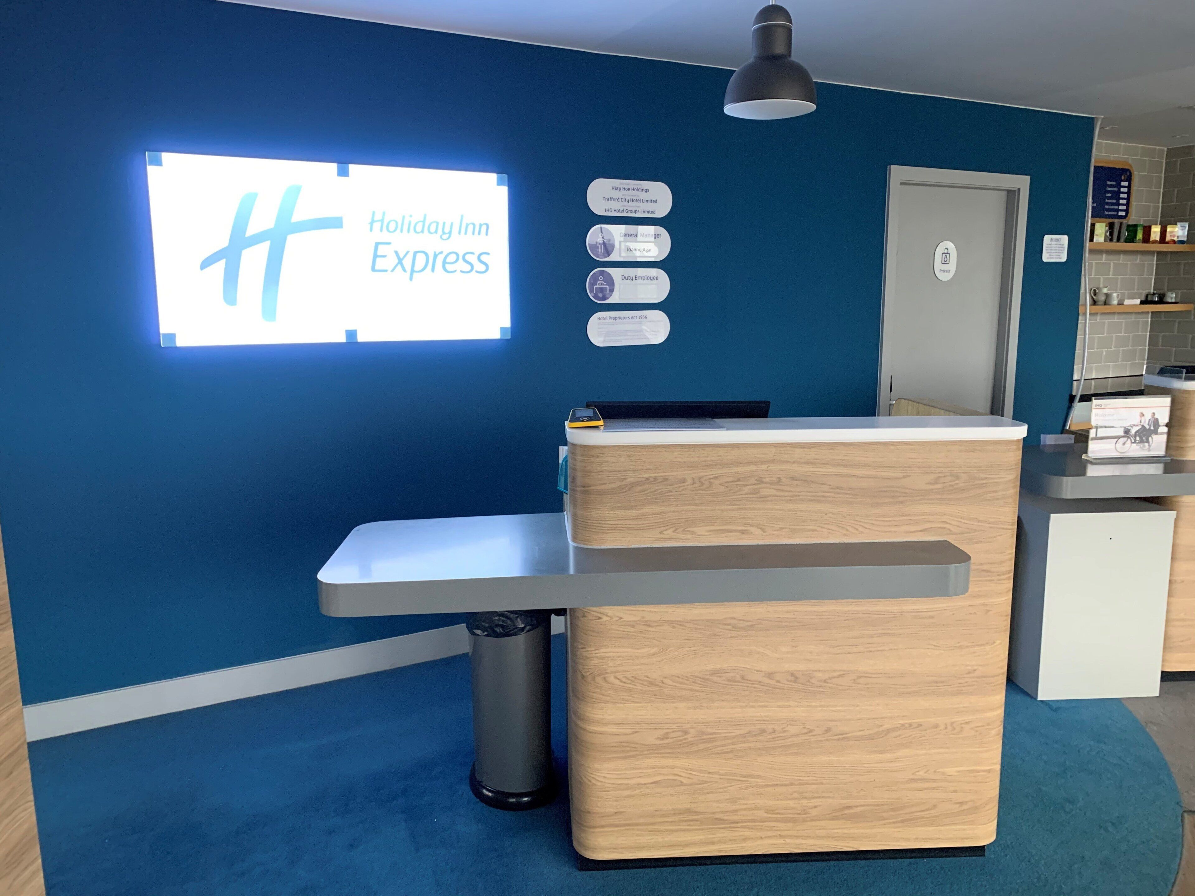 A reception desk with a Holiday Inn Express sign, a trash can, and a door to the right.