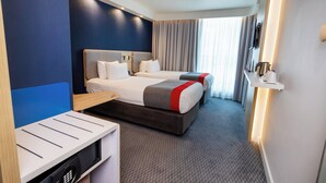 A hotel room with a large bed, a desk, a chair, and a TV.