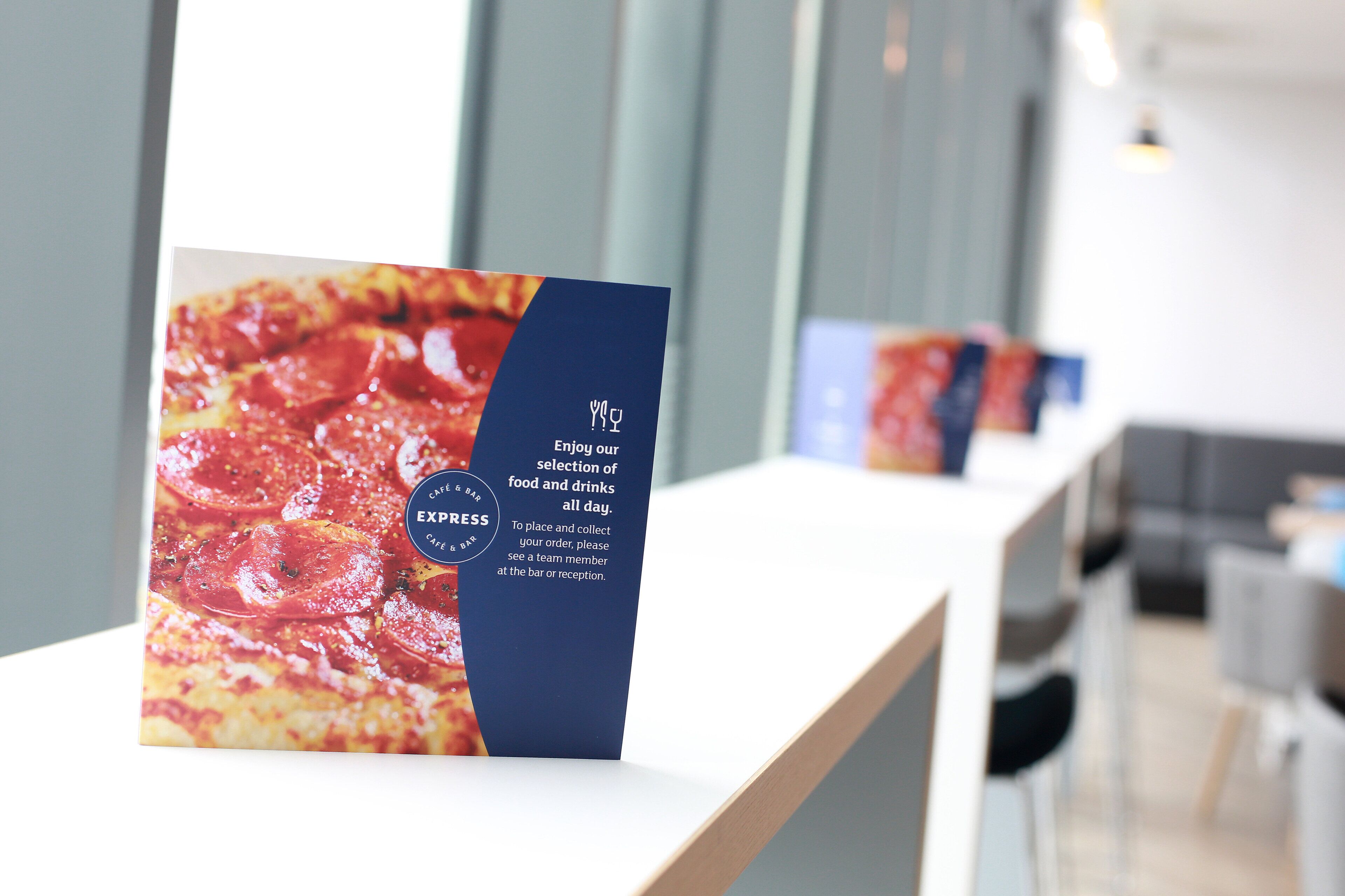 Un panneau de menu avec une image de pizza et du texte, pour un café et un bar.