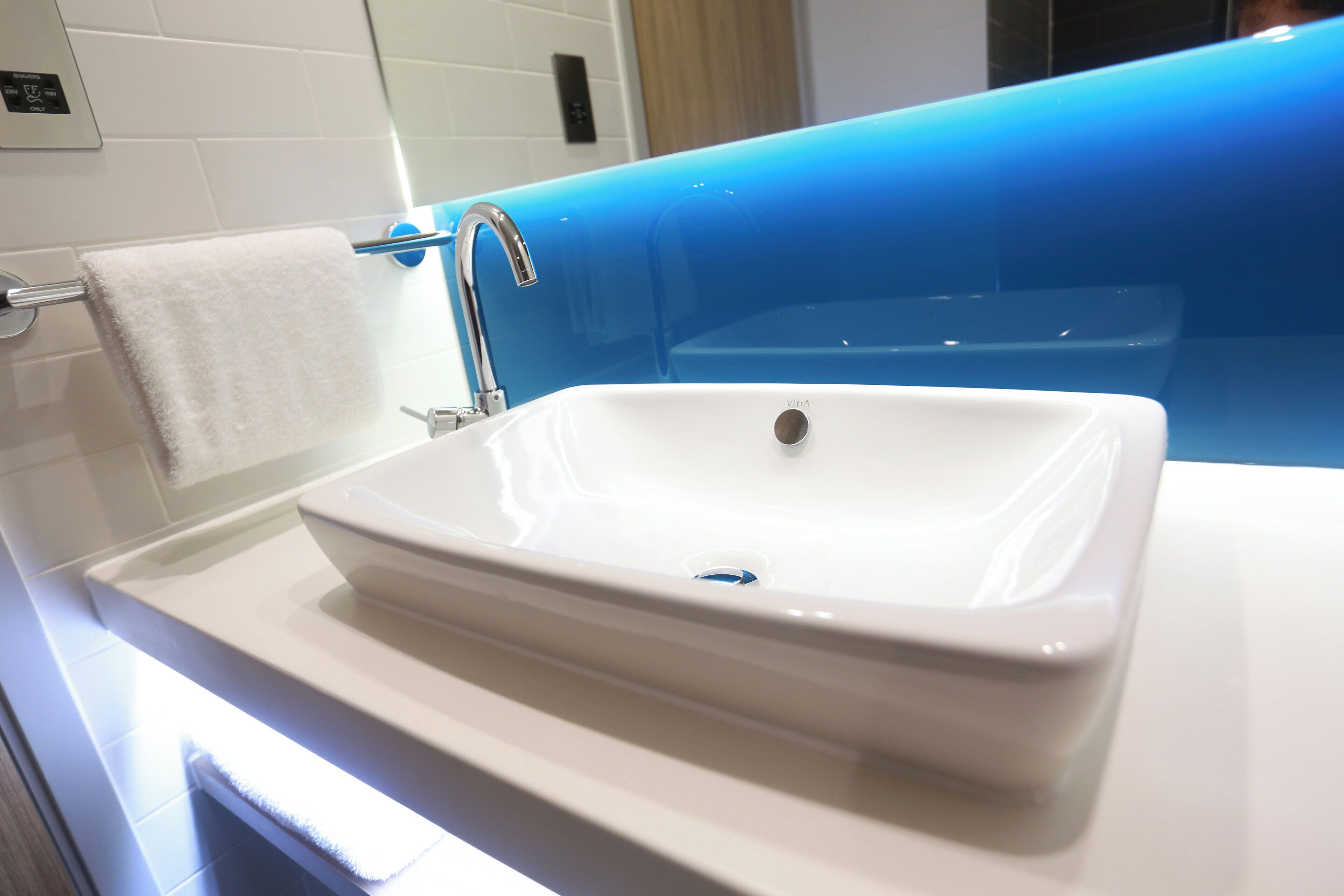 Een badkamer met een wit wastafelmeubel, een handdoekhouder en een blauwe accentmuur.