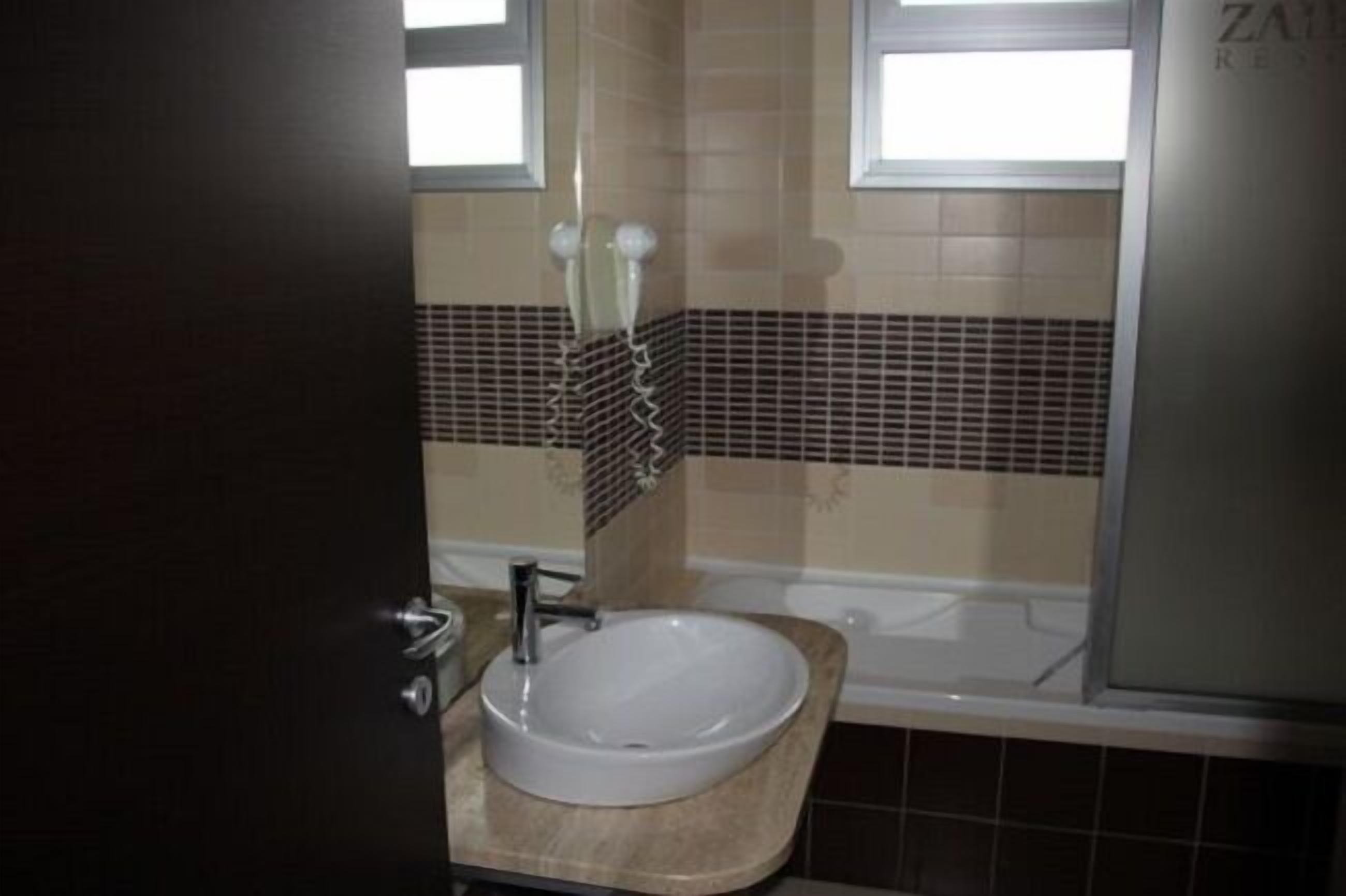 Une salle de bain avec un lavabo blanc, une baignoire et un espace douche.