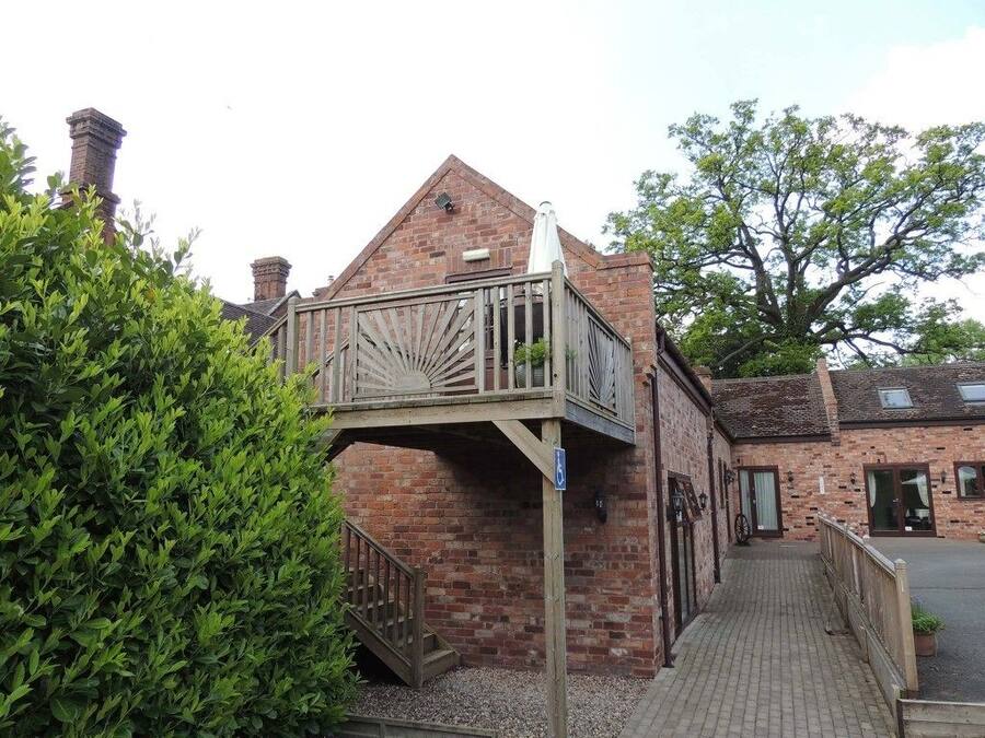 A brick building with a wooden balcony and a wheelchair-accessible ramp.