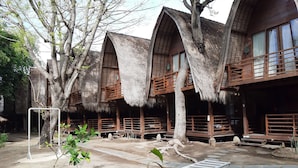 A rustic wooden building with thatched roofs and a covered outdoor seating area.
