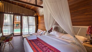 A bedroom with a large bed, a chair, and a view of the outside.