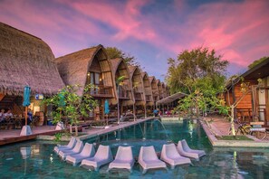 A resort with thatched-roof buildings, a swimming pool with lounge chairs, and a tropical garden setting. - Mola2 Resort Gili Air (Gili Air)