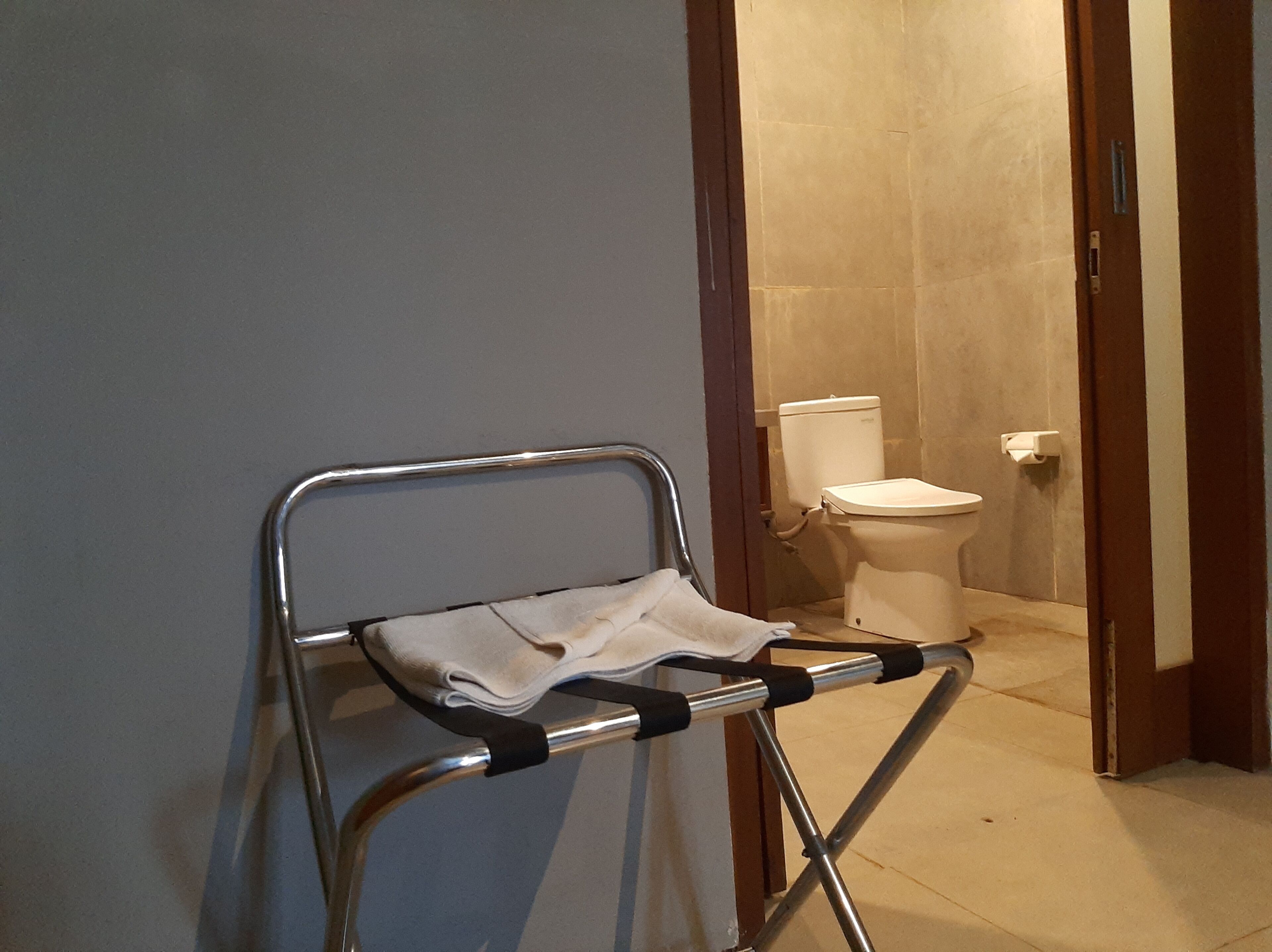 Une salle de bain équipée d’un siège de douche, de toilettes et d’un porte-serviettes.