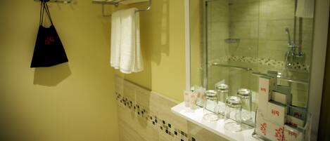 A bathroom with a mirror, a towel rack, and a shelf with toiletries.