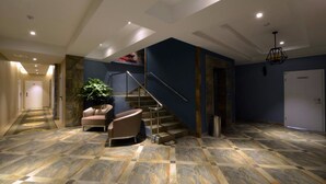 A spacious interior with a staircase, a seating area with chairs, and a potted plant. - Hotel Nine (Ulaanbaatar)