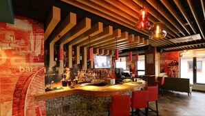 A bar area with a curved counter, red bar stools, and a television screen. - Hotel Nine (Ulaanbaatar)
