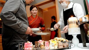 A buffet setup with various desserts and a chef serving food. - Hotel Nine (Ulaanbaatar)
