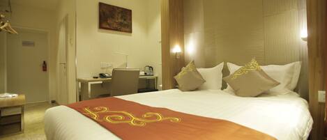 A hotel room with a large bed, a desk, and a chair.