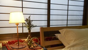 Ein Bett mit weißer Bettwäsche, einem Holzkopfteil und einem Nachttisch mit Lampe und einem dekorativen Gegenstand.