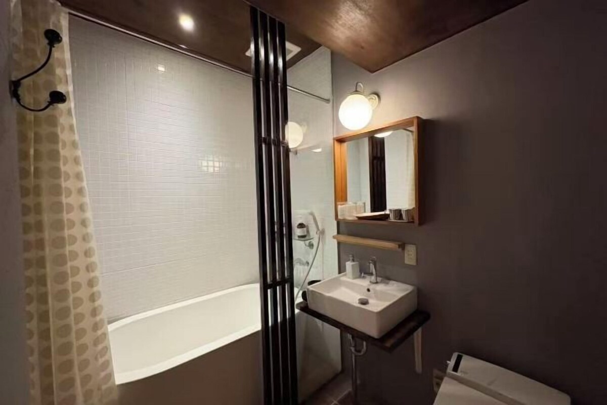 A bathroom with a bathtub, a sink, a mirror, and a shower curtain.