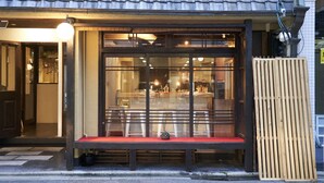 Ein Restaurant mit traditionellem japanischen Eingangsbereich, einer hölzernen Bank vor der Fassade und einem Ziegeldach.