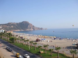Una carretera costera con una playa y una montaña al fondo.
