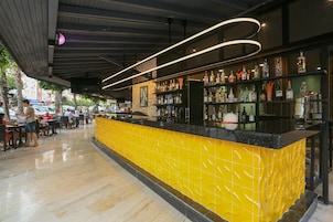 A bar area with a yellow tiled counter and a variety of bottles.