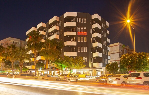 A multi-story hotel with balconies, a sign reading "ANGORA APART HOTEL," and a street with cars in motion.