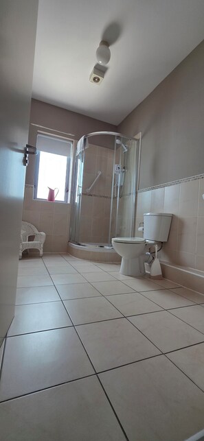 A bathroom with a shower, toilet, and a window with a view. - The Courtyard Apartments (Carrick-on-Shannon)