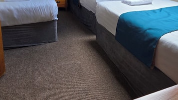 A room with two beds, a skylight, a ceiling fan, and a small table.
