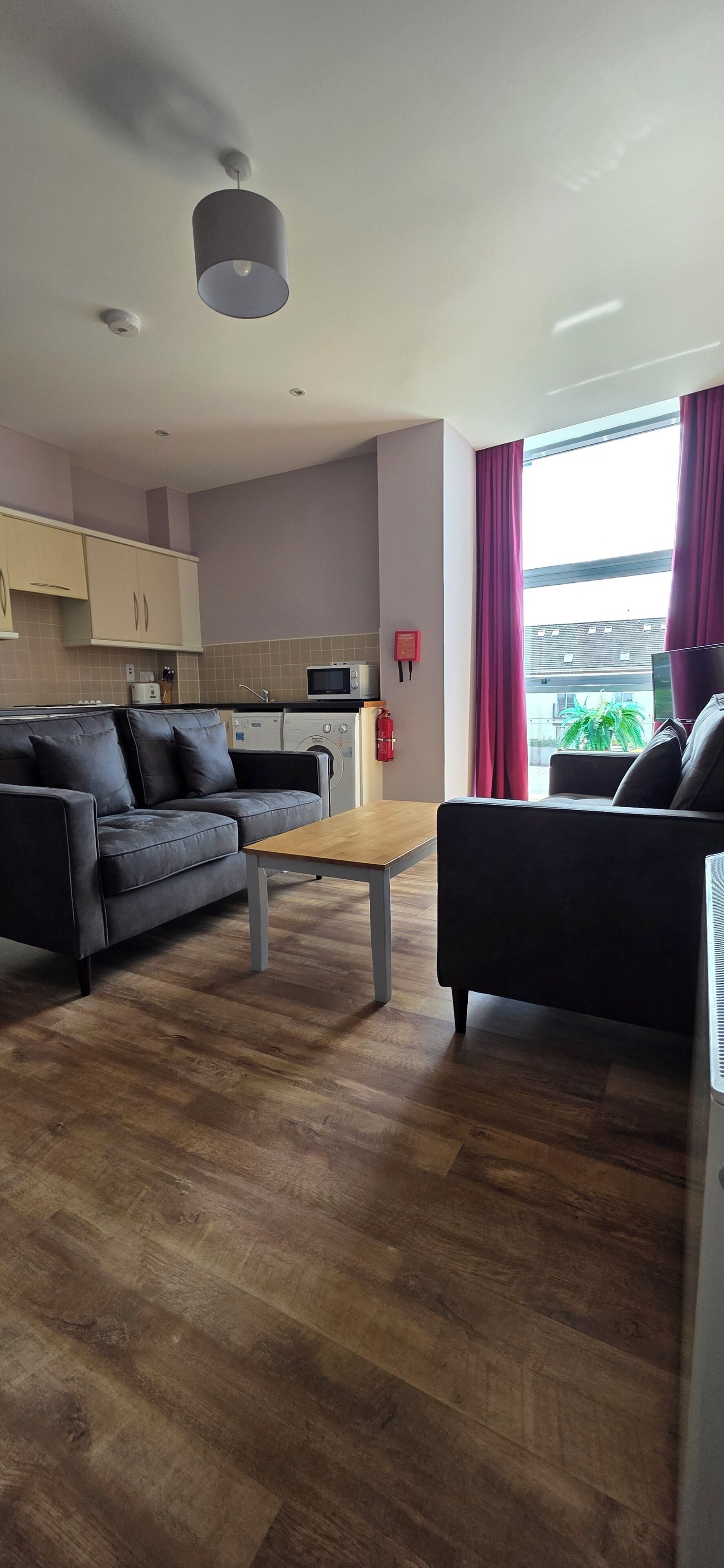 A modern living room with a sofa, a coffee table, and a kitchen in the background.