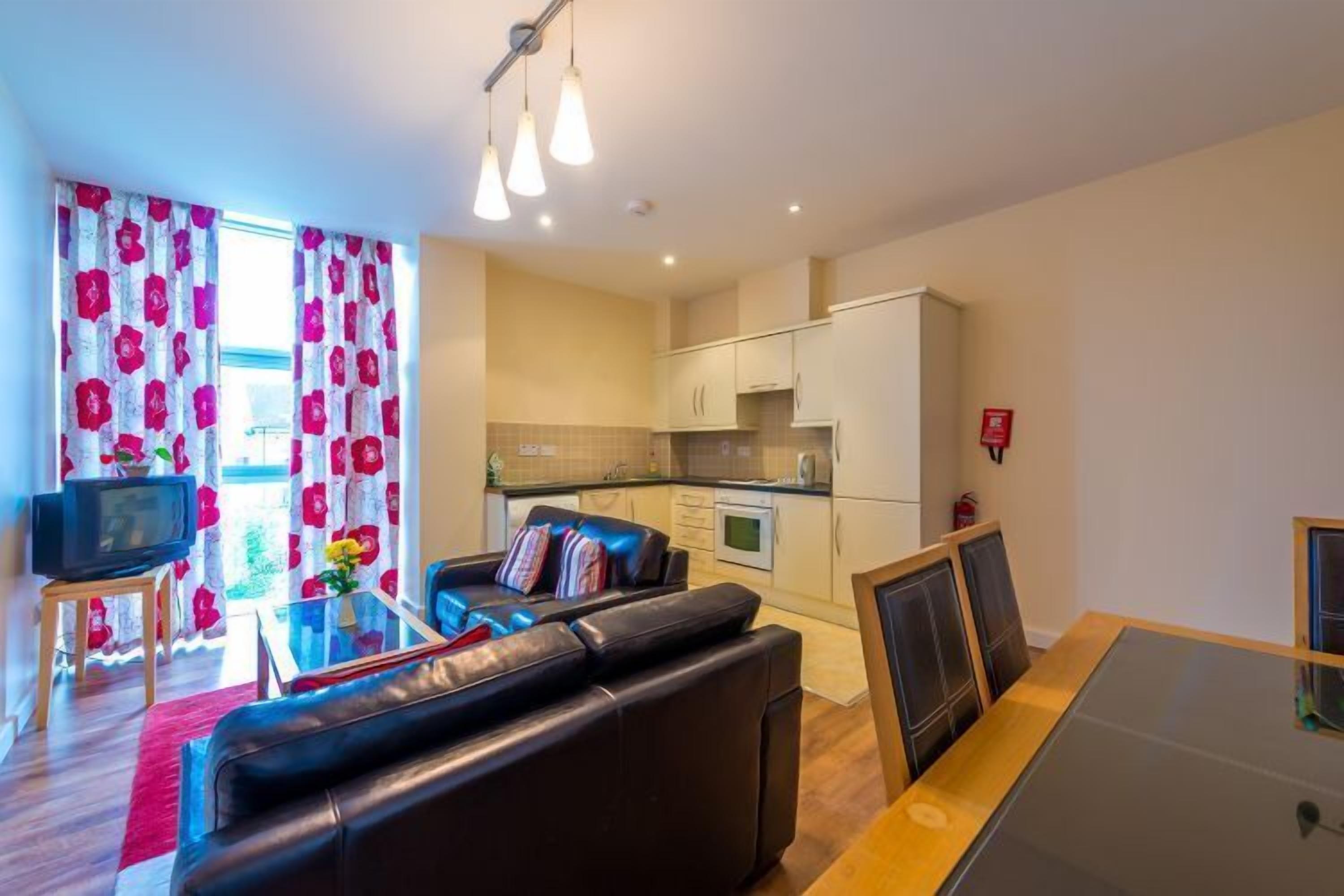 A compact living space with a sofa, a dining table, a TV, and a kitchenette.