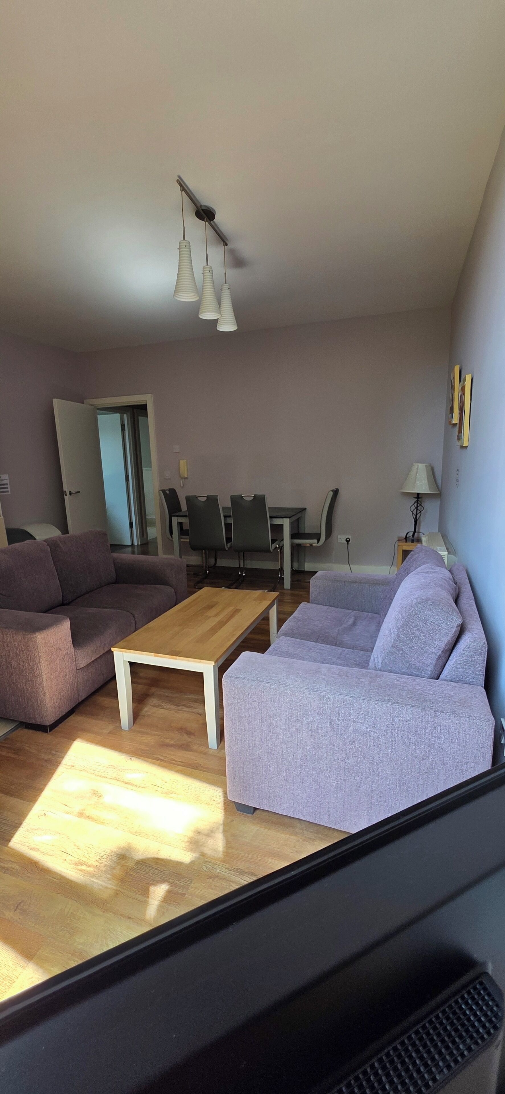 A living room with a sofa, a coffee table, and a dining table with chairs.