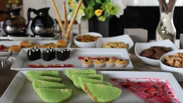 A buffet table with various food items including green pastries, cupcakes, and a dessert with strawberries.