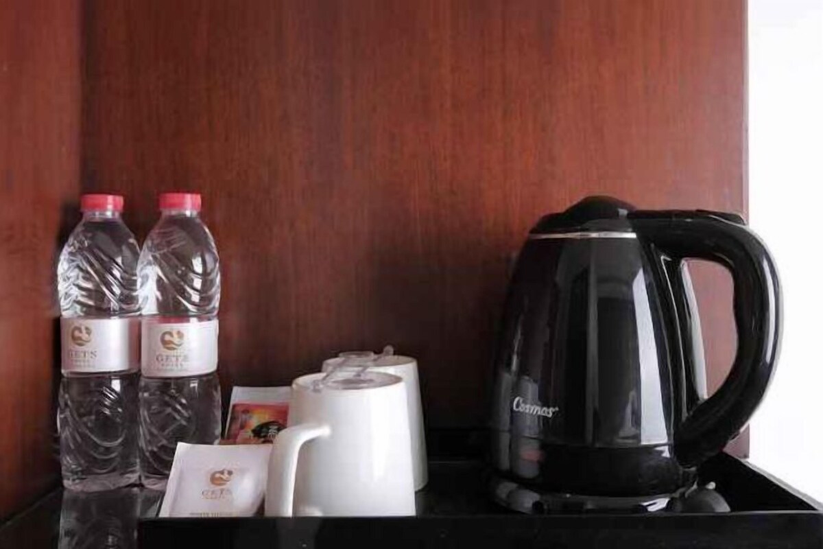 Una cafetera negra y dos botellas de agua con tapas rojas sobre una superficie de madera.