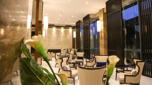 Un moderno vestíbulo de hotel con zonas de estar, ventanas amplias e iluminación decorativa.