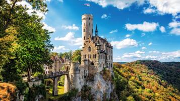 Um castelo no alto de um penhasco, com uma ponte que o acessa.