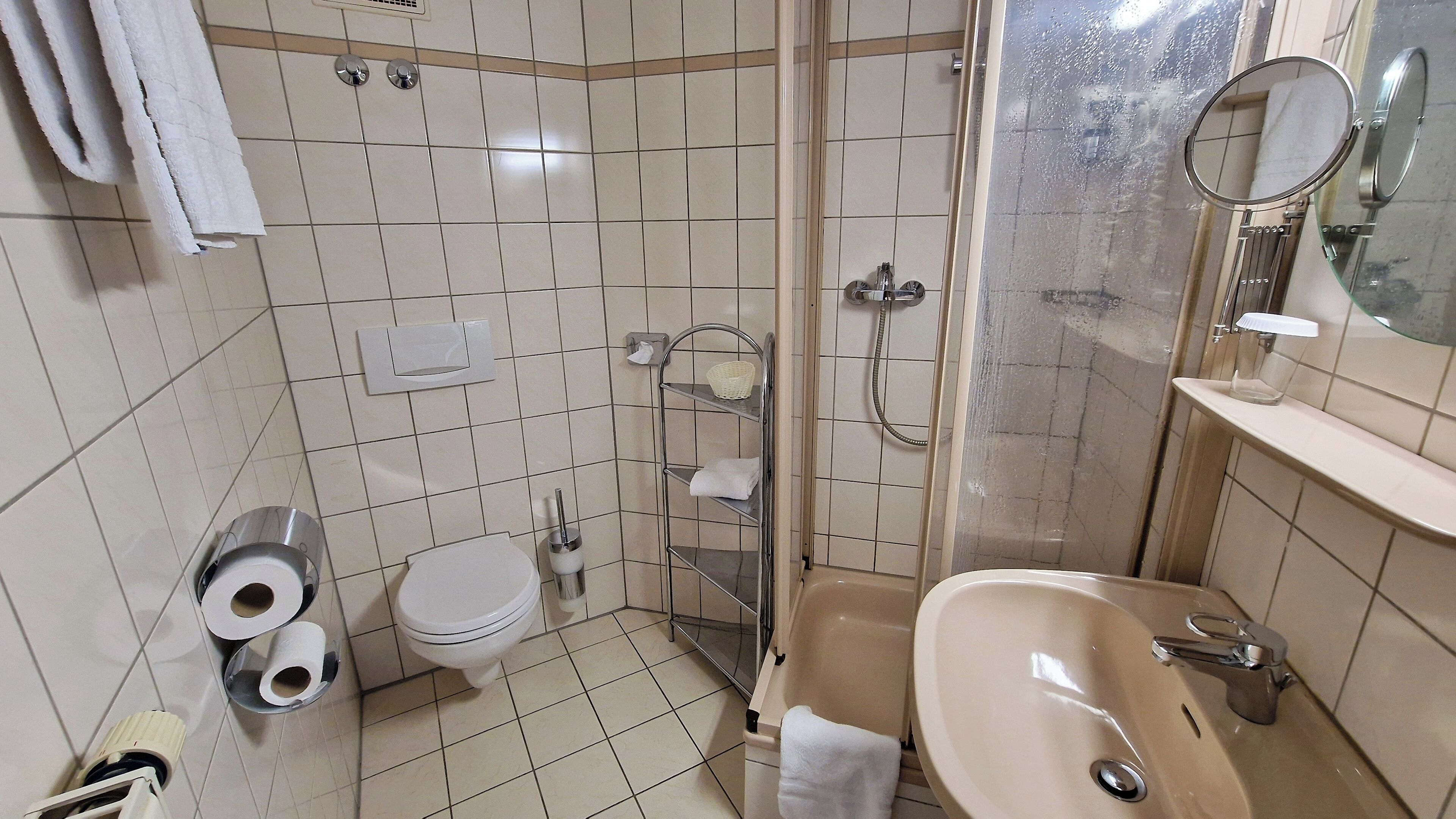A bathroom with a toilet, bidet, shower, and sink.