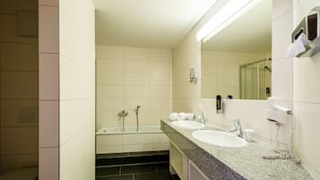 A modern bathroom with two sinks, a bathtub, and a toilet.