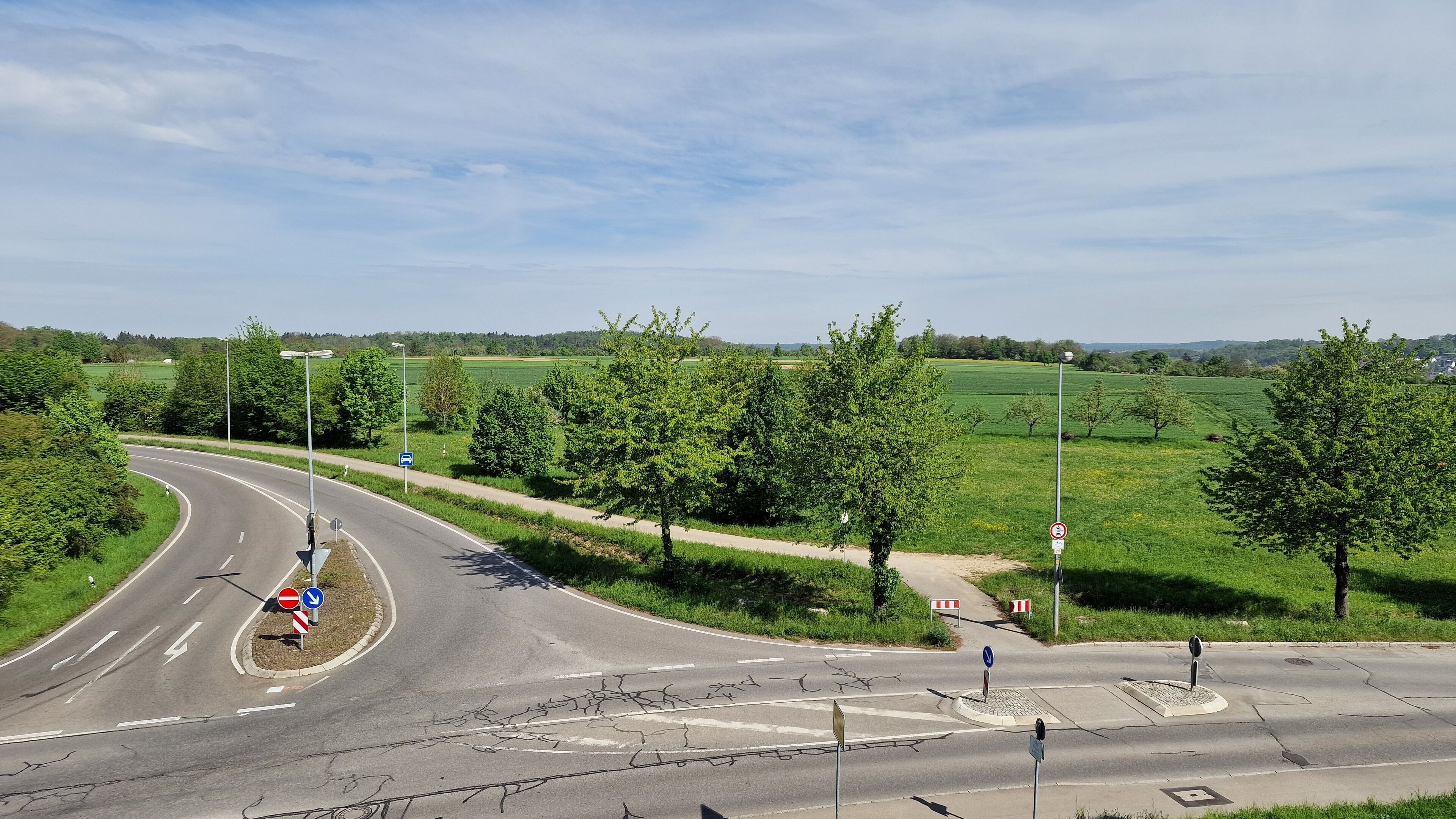 Ein Kreisverkehr mit deutlicher Straßenführung, Verkehrsschildern und angrenzender Bepflanzung.
