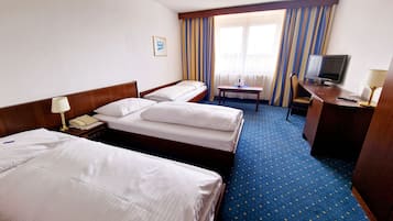 Ett hotellrum med två separata sängar, ett skrivbord med en stol, en tv och ett litet bord.