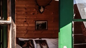 A wooden cabin interior with a bed, a mounted deer head, and a framed picture on the wall. - Weigl Hütte (Semmering)