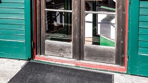 A wooden door with green trim and a red frame, partially open, revealing a window with curtains. - Weigl Hütte (Semmering)