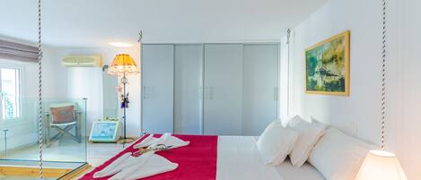 Una habitación de hotel con cama, escritorio, silla, armario y un cuadro en la pared.