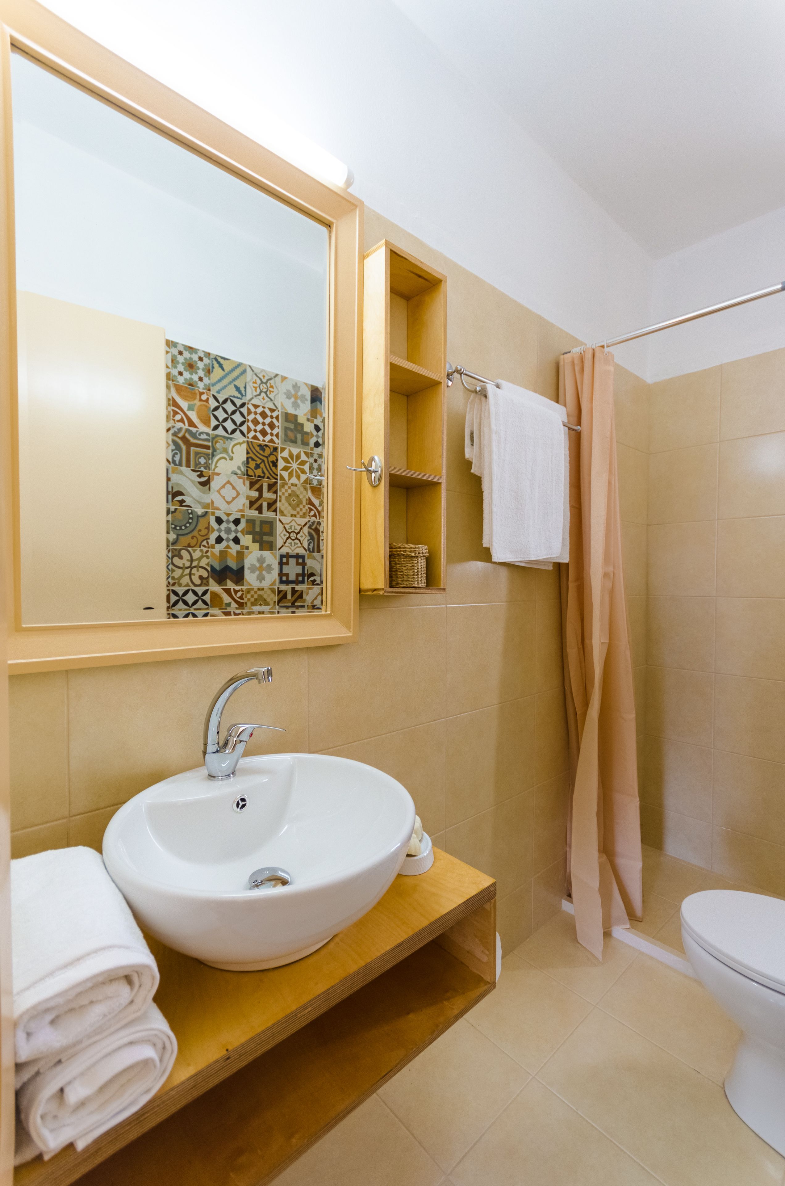 A bathroom with a large mirror, a sink, a toilet, and a shower curtain.