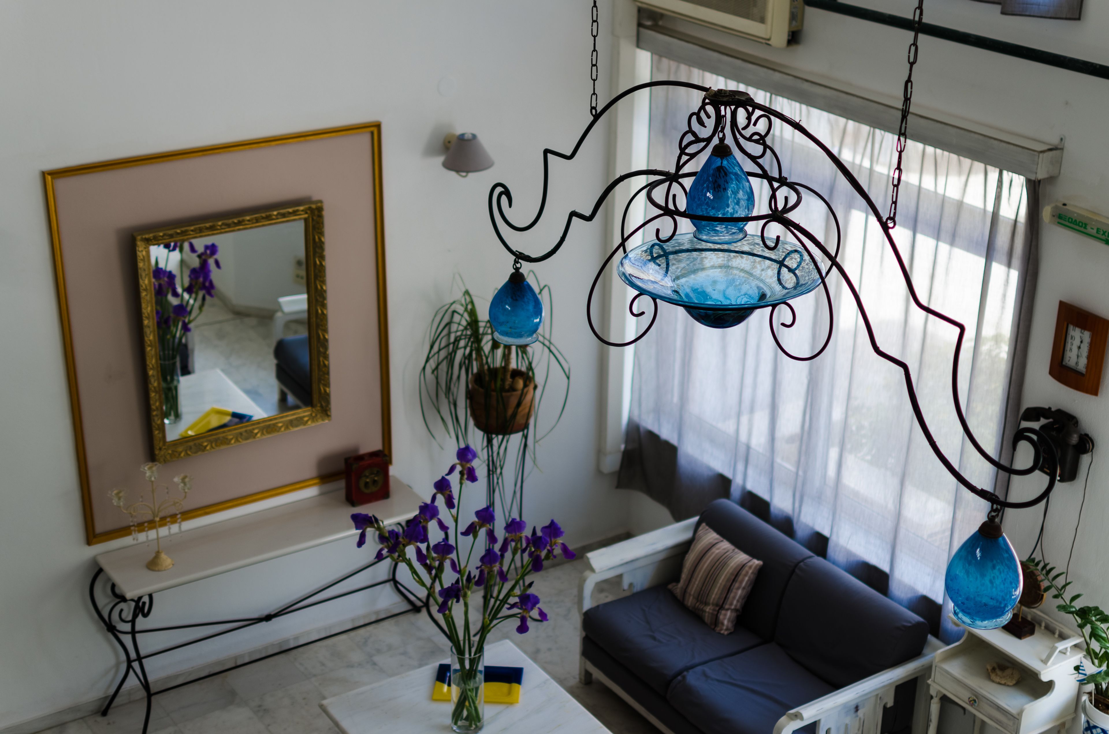 Una sala de estar con un sofá, un espejo y lámparas de vidrio azul colgantes.