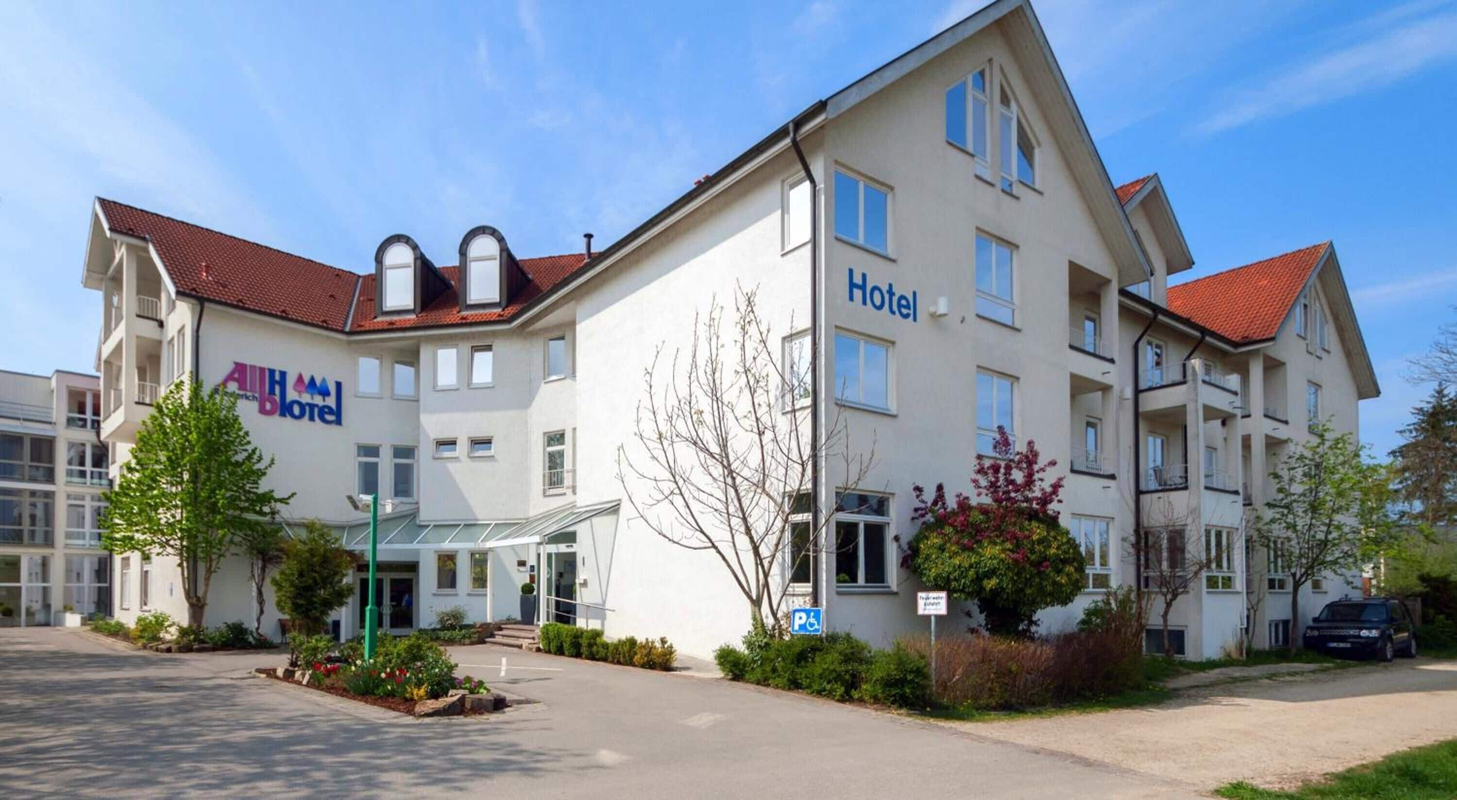 A hotel with a modern design, featuring a central entrance, multiple windows, and a parking sign.