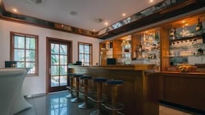 A bar area with stools, a counter, and a view of the outdoors through large windows. - Albhotel Fortuna (Riederich)