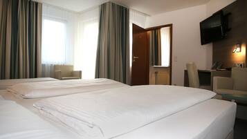 A hotel room with two beds, a desk, a chair, a television, and a door.