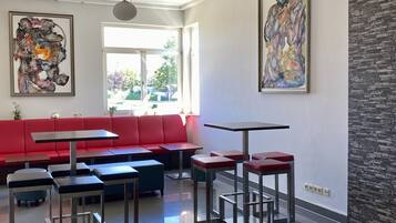 A modern interior with a red sofa, multiple tables, and abstract art on the walls.