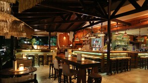 A bar area with wooden furniture, hanging lights, and a bar counter. - Hotel Magdalena (Kassandra)
