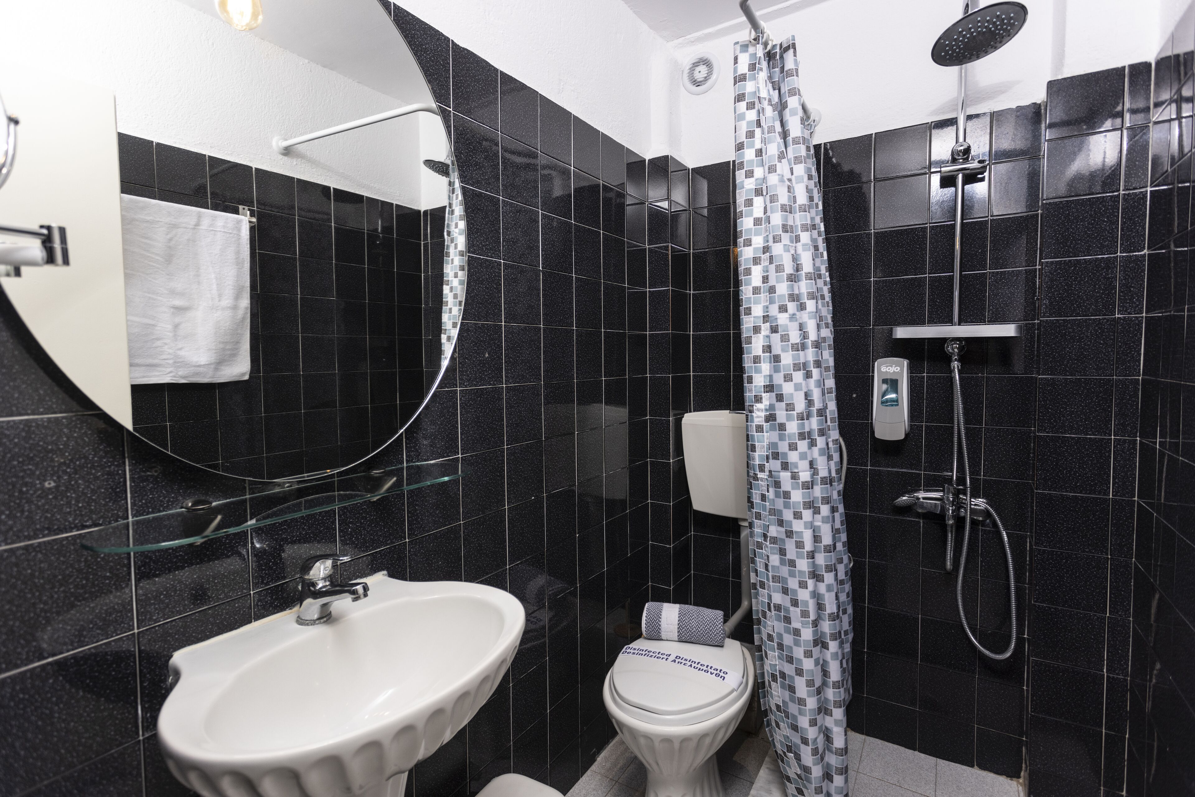 Un baño con un lavabo blanco, inodoro, ducha y espejo.