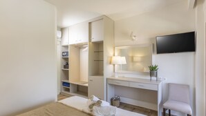 A hotel room with a bed, a desk, a chair, a TV, a wardrobe, and a mirror. - Hotel Magdalena (Kassandra)
