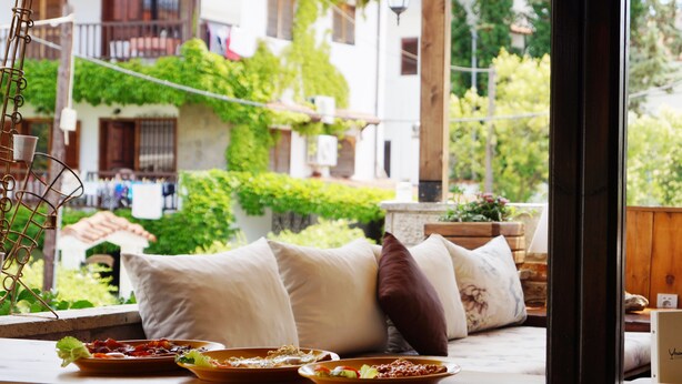 A cozy seating area with a view of a garden and buildings, featuring a table with plates of food and a window with a view of a balcony. - Hotel Magdalena (Kassandra)